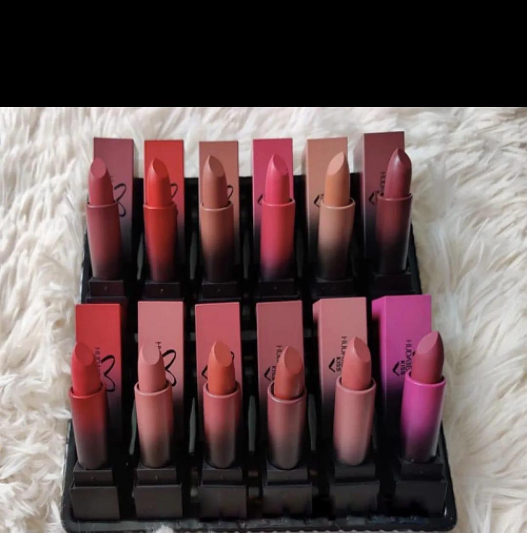 Set of twelve matte nude and pink lipsticks in square tubes on white fur background
