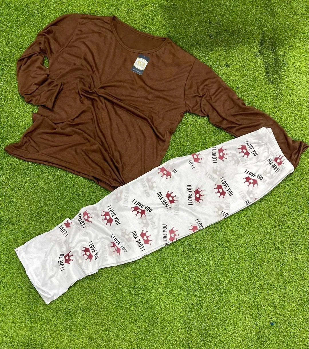 Brown long sleeve pajama top and white pants with red crowns and 'I love you' text on grass