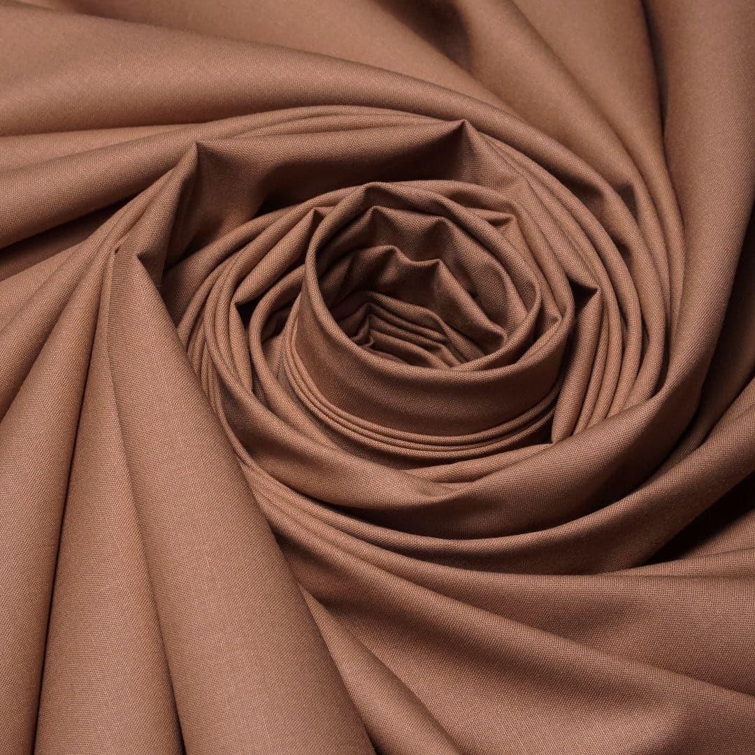 Close-up of brown cotton fabric with smooth texture, arranged in a spiral pattern