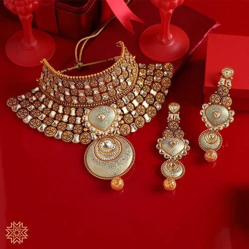 Traditional gold necklace and earrings set with intricate design on red background