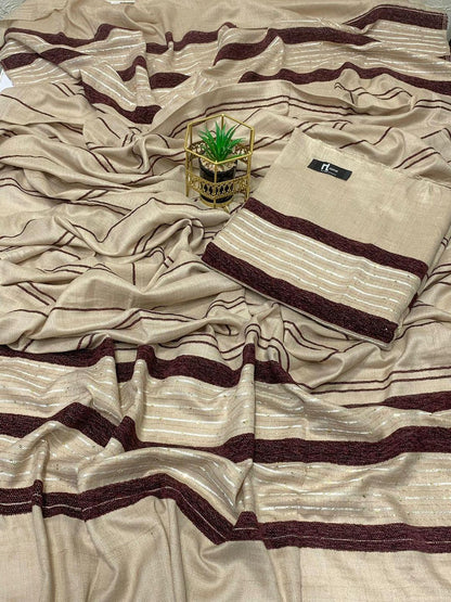 Beige saree with maroon and gold stripes, folded neatly, with a small potted plant nearby