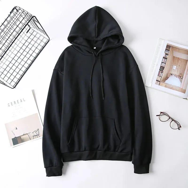 Black hoodie sweatshirt with drawstrings flat lay, styled with glasses, magazines, and wire basket