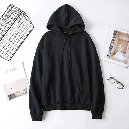 Black hoodie sweatshirt with drawstrings flat lay, styled with glasses, magazines, and wire basket