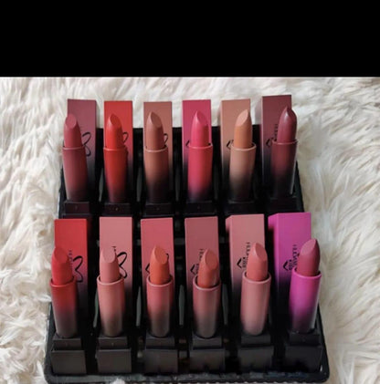 Set of twelve matte nude and pink lipsticks in square tubes on white fur background