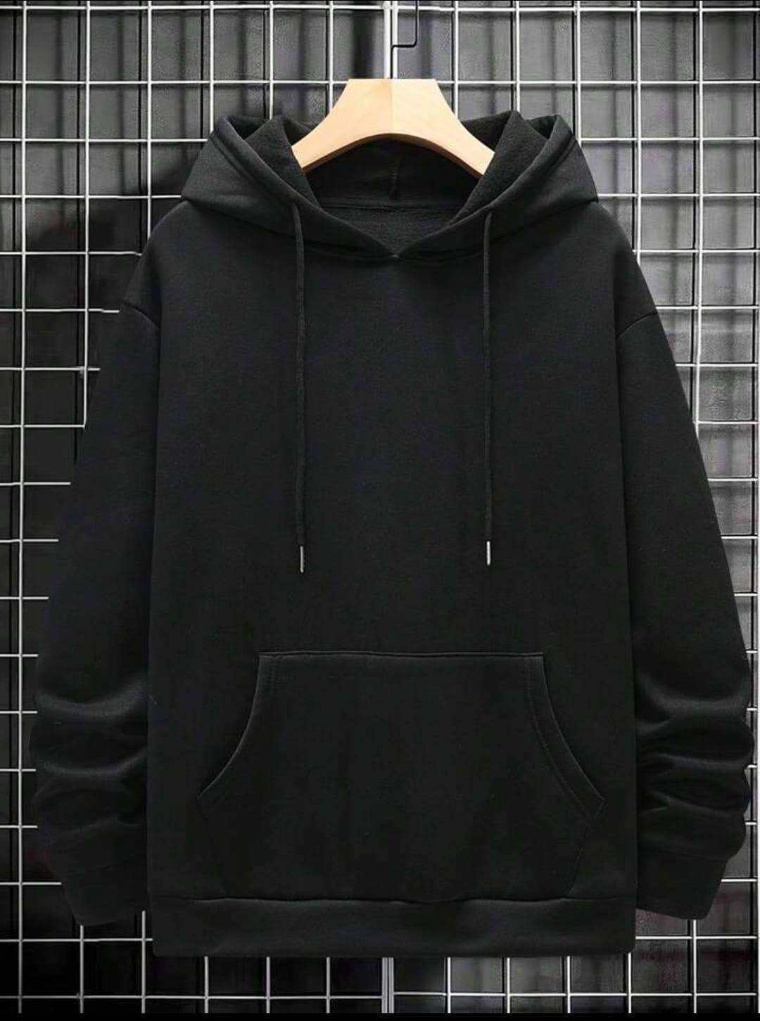Black hoodie with front pocket and drawstrings displayed on hanger against grid wall
