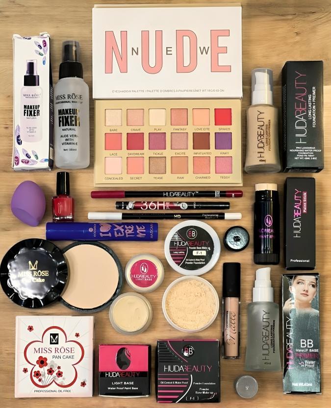 Makeup kit with nude eyeshadow palette, Huda Beauty products, face powders, and fixers on table