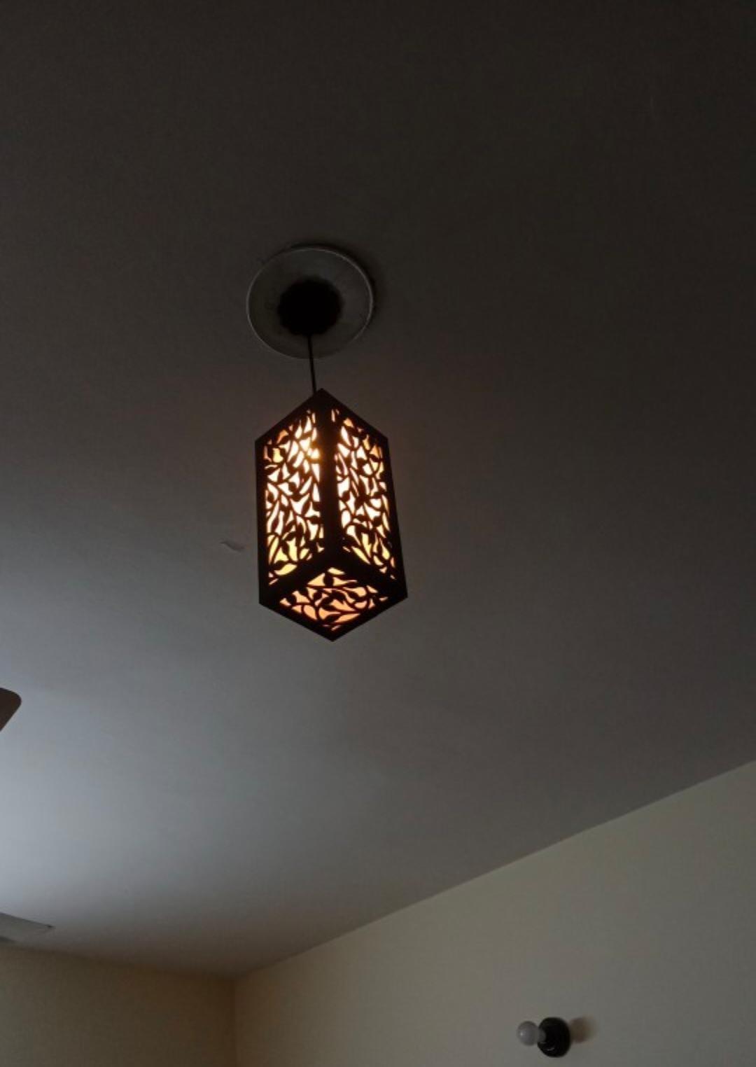 Decorative ceiling pendant light with intricate geometric cut-out design, glowing warmly