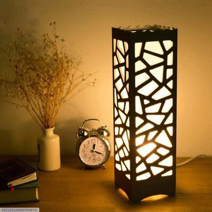 Decorative geometric table lamp on wooden nightstand with clock, vase, and books