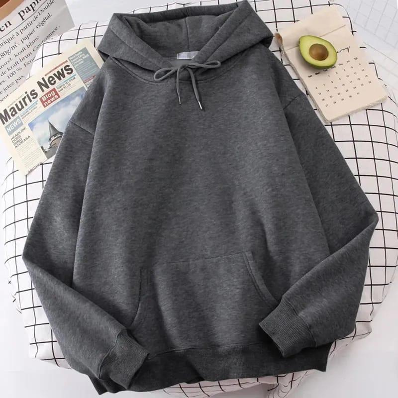 Dark gray hoodie with drawstring on white grid bed, newspaper and half avocado nearby