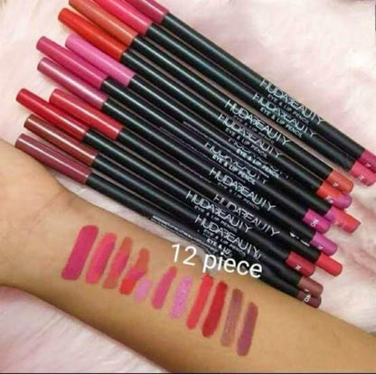 Huda Beauty 12 piece lip liner set with swatches on arm, assorted pink and red shades