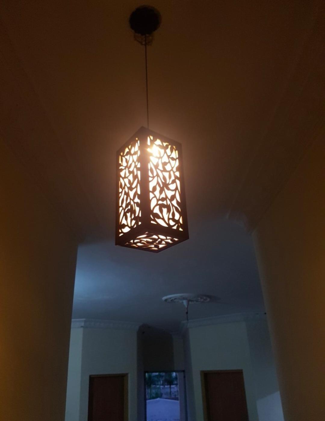 Decorative hanging lantern light fixture in a dim hallway with patterned cutouts.