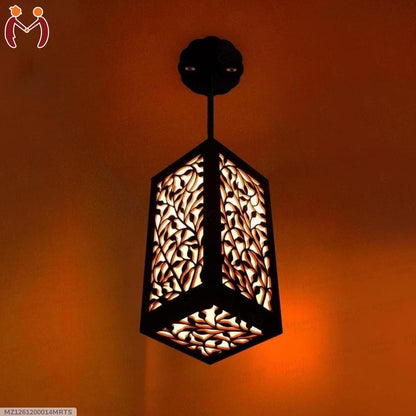 Decorative hanging pendant light with ornate leaf pattern glowing on orange ceiling