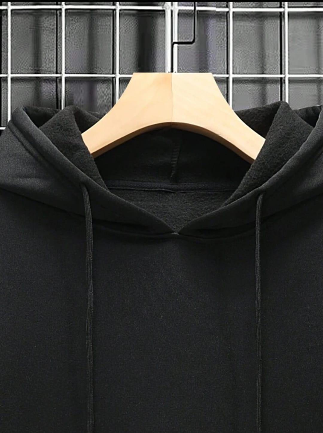 Black hoodie on wooden hanger against metal grid background