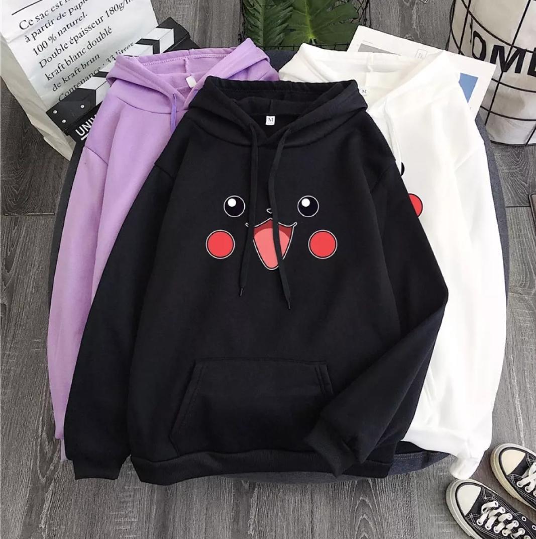 Three hoodies in black, purple, and white with a cute cartoon face, laid on wooden floor