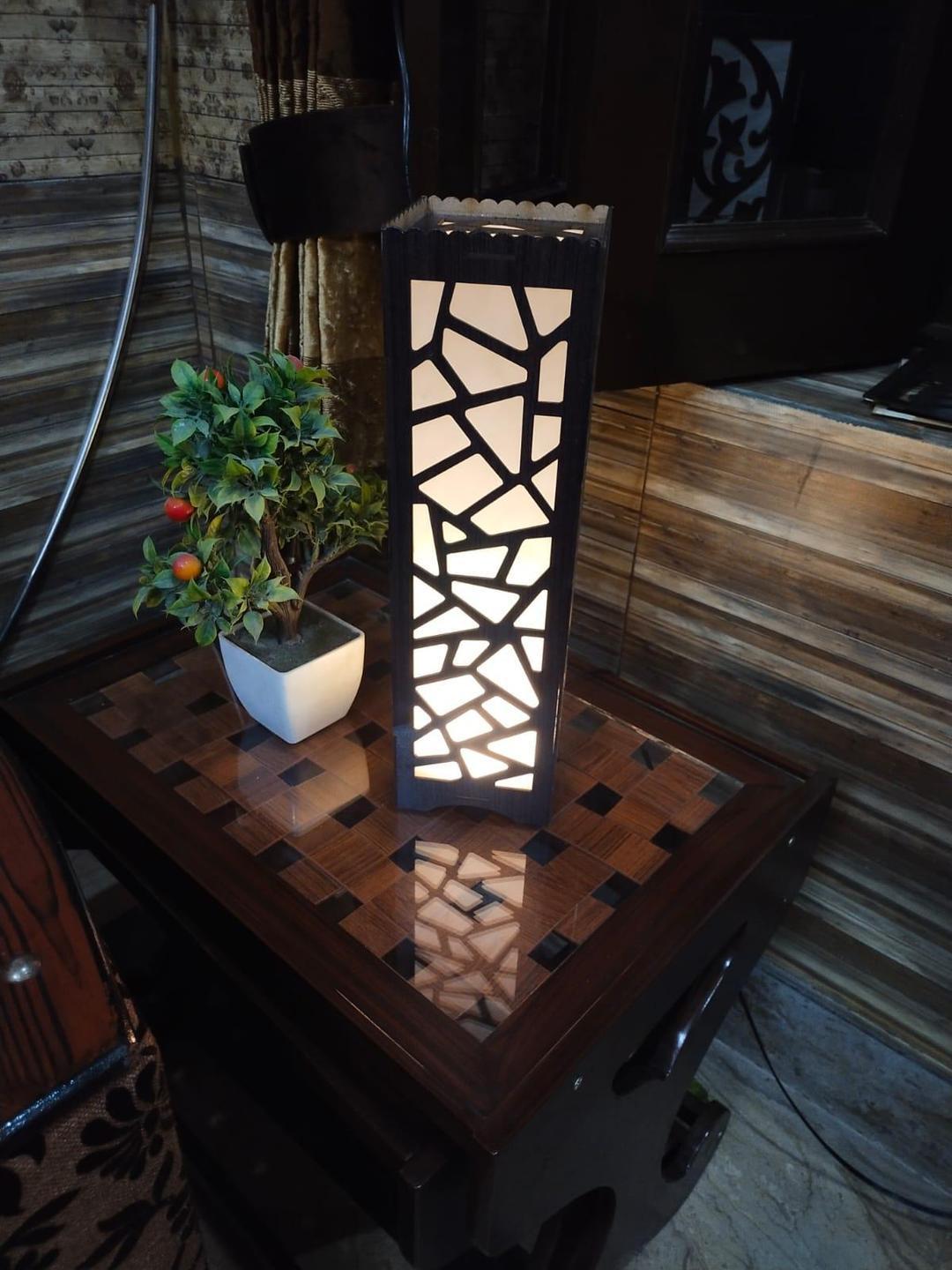 Modern geometric table lamp with potted plant on wooden side table in cozy room